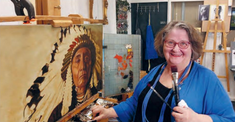 Antoinette Vunderink in haar schildersatelier in Apeldoorn, met penselen voor een groot olieverfportret